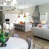 A dining room table and chairs in front of a kitchen.