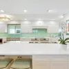 A kitchen with white cabinets and green walls.