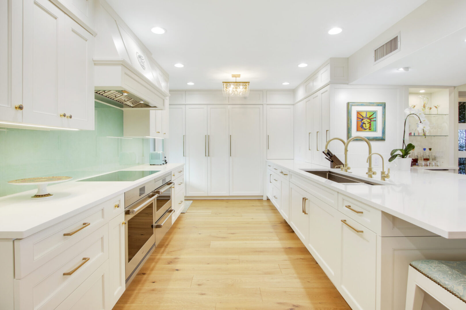 A kitchen with white cabinets and wooden floors.