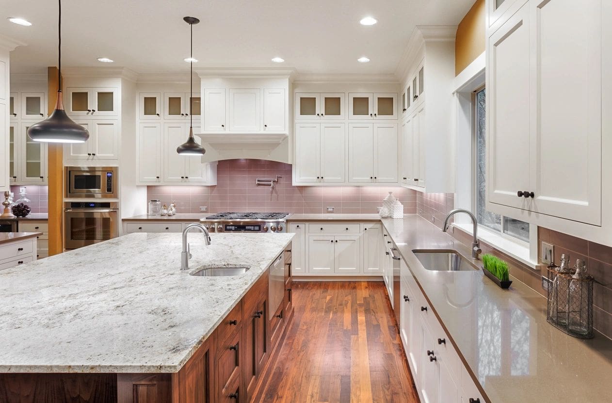 A large kitchen with white cabinets and wood floors.