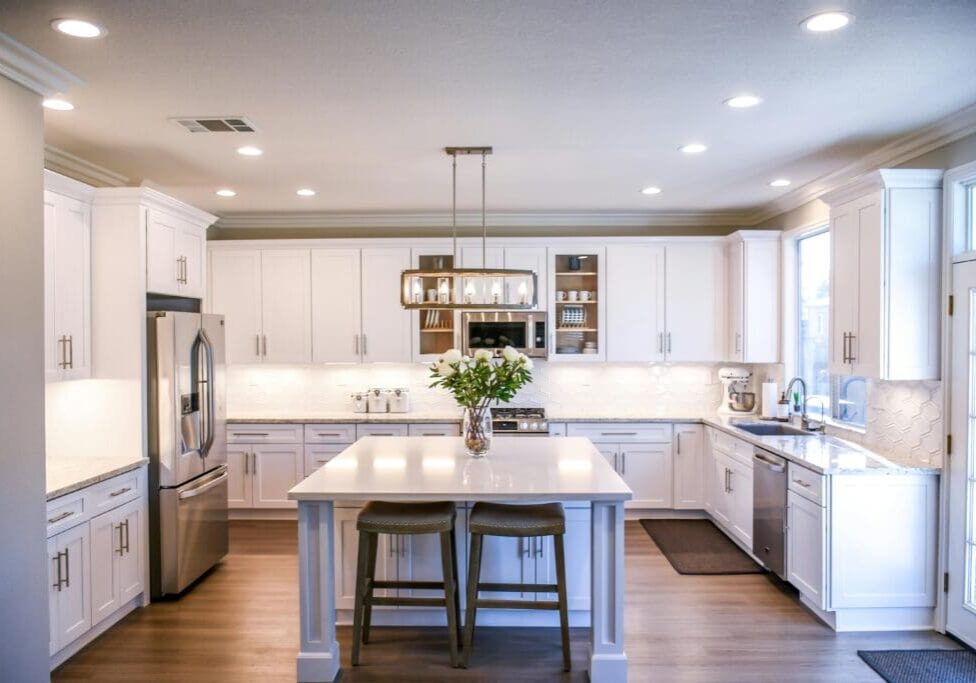 A kitchen with white cabinets and wooden floors.